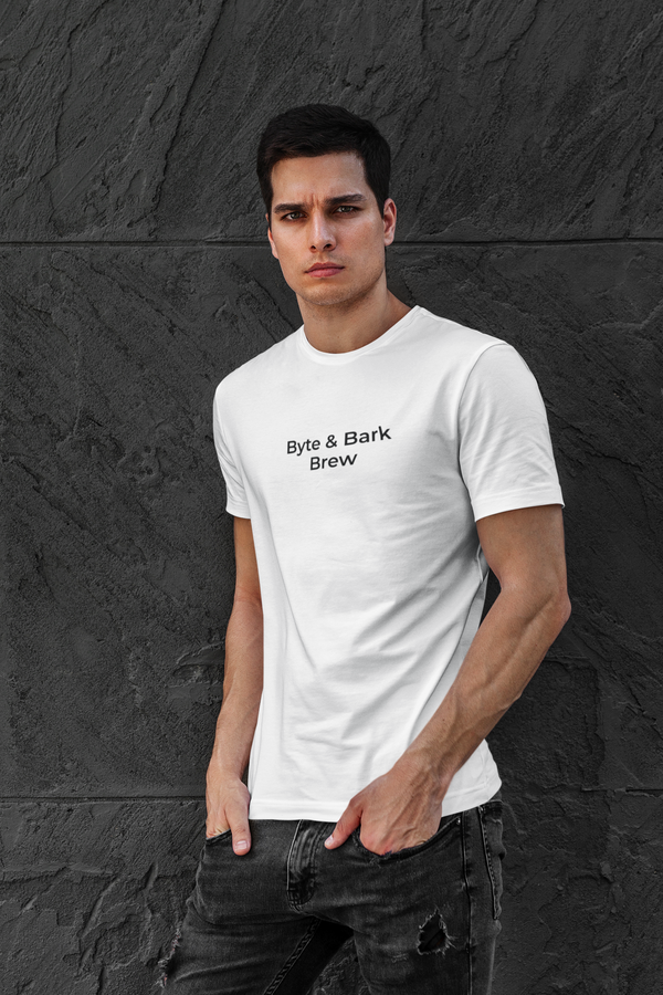 Man wearing a white Byte & Bark Brew t-shirt with text against a dark stone wall