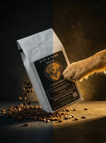 Dog paw reaching for a coffee bag labeled 'Byte & Bark Brew' with scattered coffee beans on a dark background.