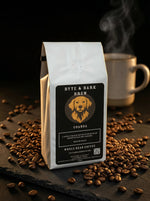 Coffee bag labeled 'Byte & Bark Brew' with coffee beans and a steaming cup in the background