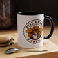 White mug with black interior and handle, featuring 'Byte & Bark Brew' logo on a wooden surface with coffee beans and a spoon.