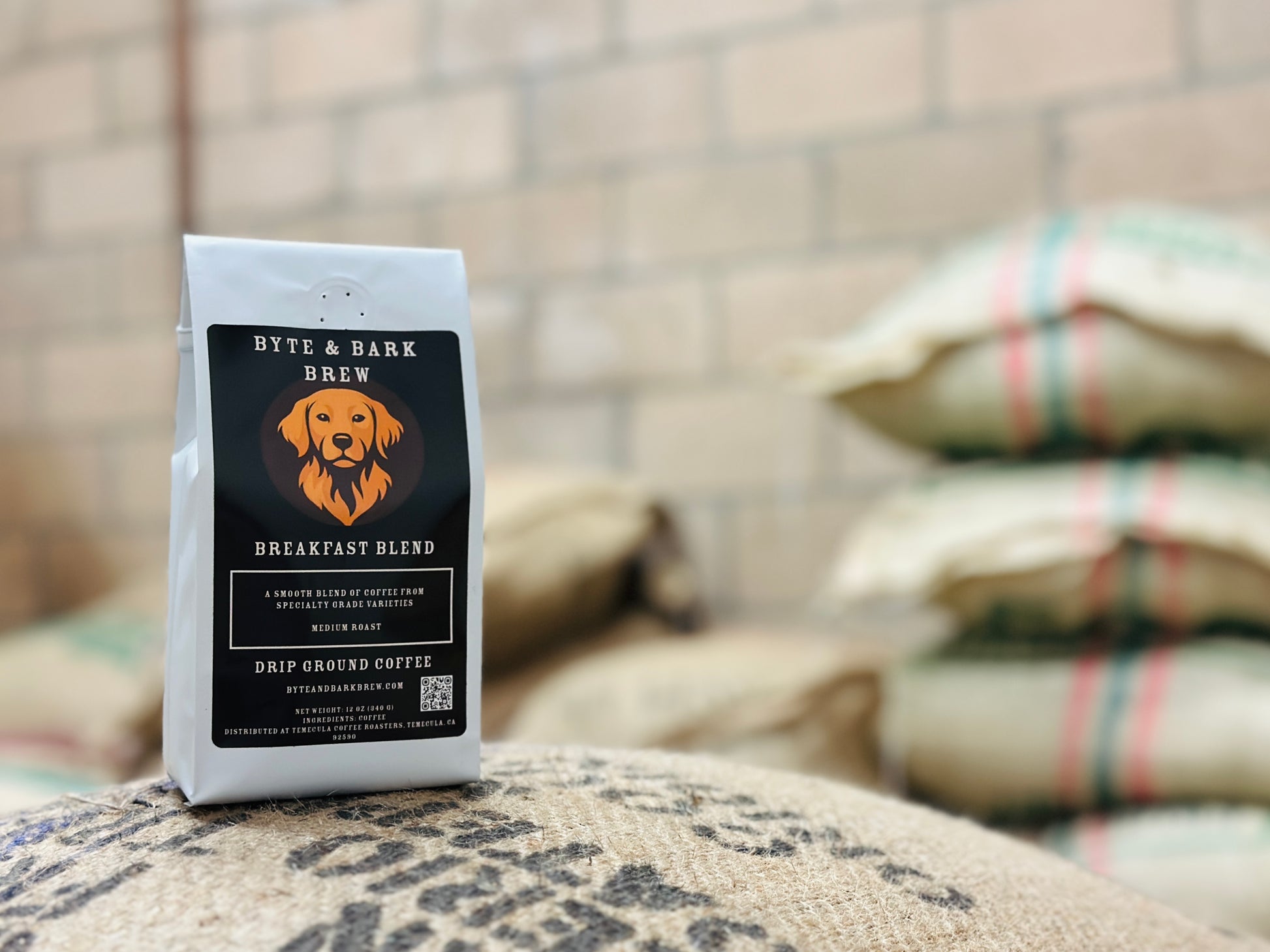Bag of Byte & Bark Brew Breakfast Blend coffee resting on imported burlap coffee bags — highlighting the brand’s commitment to quality sourcing.