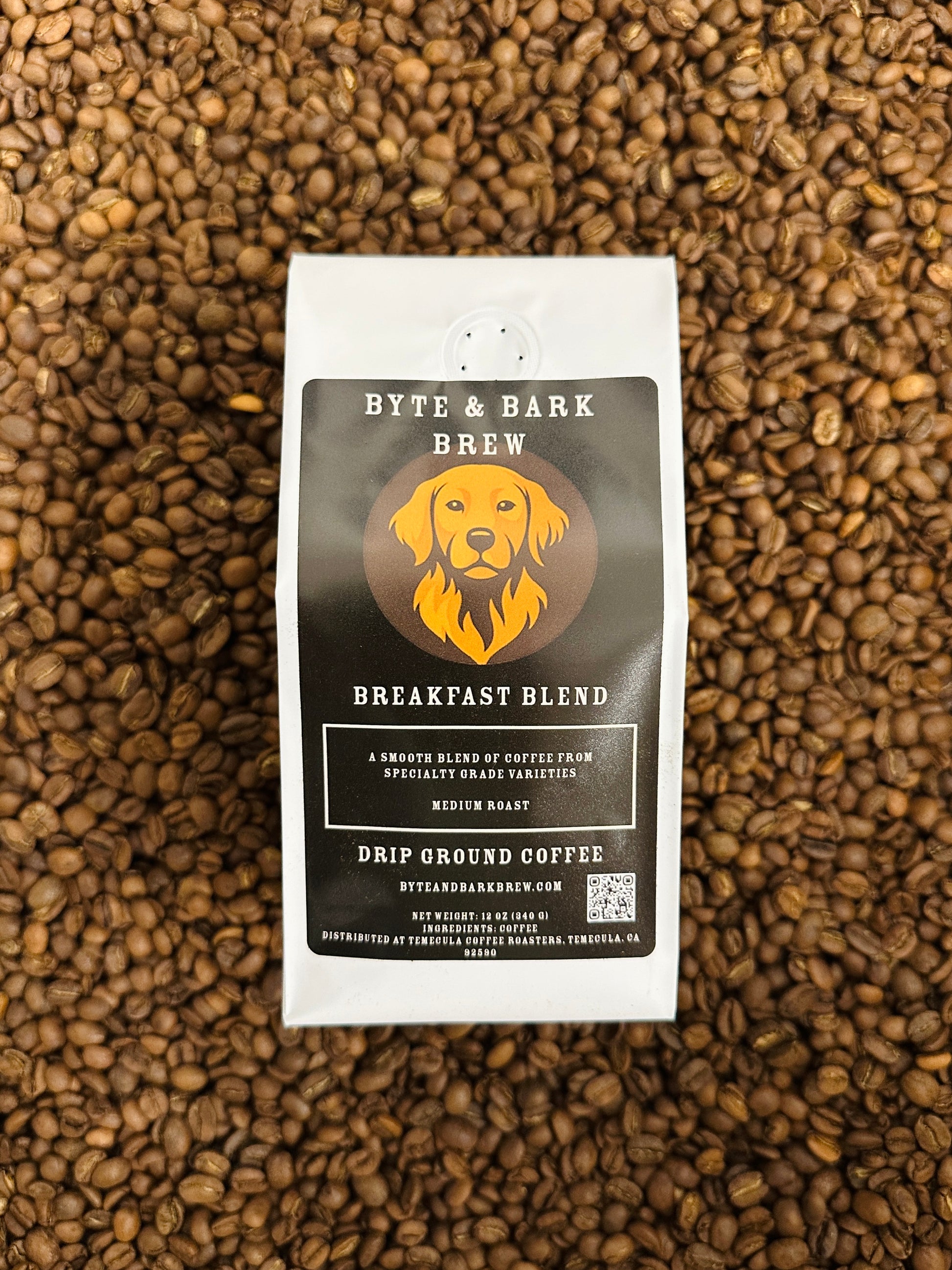 Bag of Byte & Bark Brew coffee resting on a bed of roasted coffee beans.